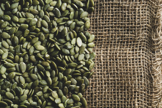 Green pumpkin seeds on rustic burlap for healthy food, nutrition, and organic concepts.