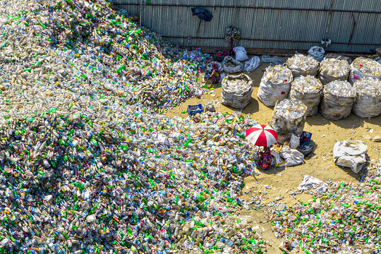 Aerial view of a large plastic recycling facility with massive piles of sorted plastic bottles and workers organizing materials in Chattogram, Chittagong Division, Bangladesh.