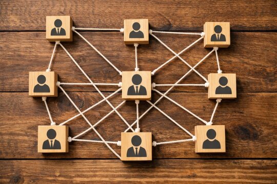Wooden blocks with human icons connected by strings on a wooden surface, symbolizing networking and organizational relationships.