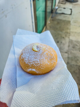 Tette delle Monache pastry from Bari dusted with powdered sugar on white napkin, traditional Italian filled doughnut close-up, concept of southern Italy street food