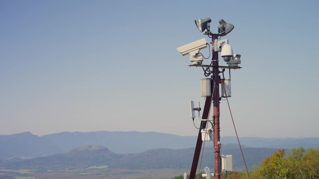 Network of surveillance cameras and antennas on pole monitoring vast mountain landscape. Security technology and environmental observation in remote location in Japan. Disaster protection station