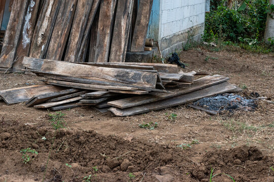 Old Reclaimed Wooden Planks Stacked Against Wall at Construction Site, Weathered Timber Boards Piled Outdoors for Reuse and Building Materials