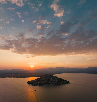 Aerial view of Janitzio island in Lake Patzcuaro at sunset with golden light reflecting on the water and mountains in the background, Janitzio, Michoacan, Mexico.