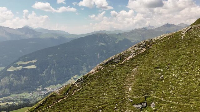 ⁠Cinematic aerial drone orbit shot flying around a dramatic mountain ridge with green slopes and deep valley view above Vipiteno in the Italian Alps.⁠