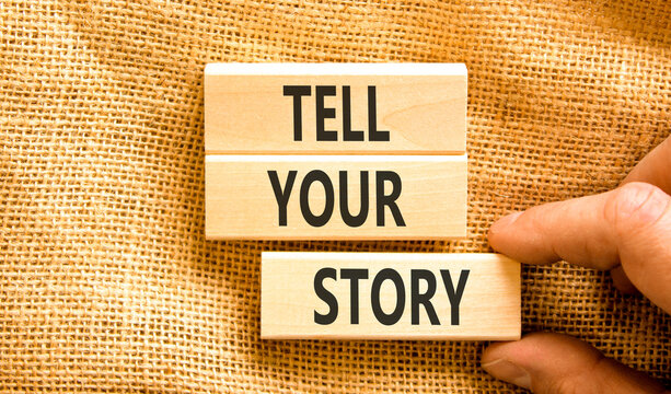Tell your story symbol. Concept word Tell your story on beautiful wooden blocks. Beautiful canvas table canvas background. Businessman hand. Business tell your story concept. Copy space.