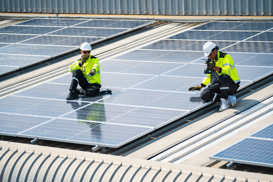 Solar electricity power technology for sustainable energy, solar panel worker roof safety helmet reflective vest inspection renewable energy maintenance photovoltaic technician inspecting rooftop