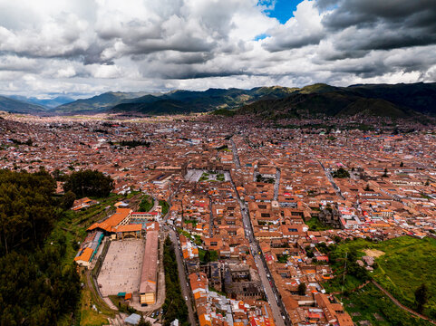 Aerial view of the historic city of Cusco, featuring dense terracotta rooftops, colonial architecture, and surrounding Andean mountains in Cusco, Cusco, Peru.