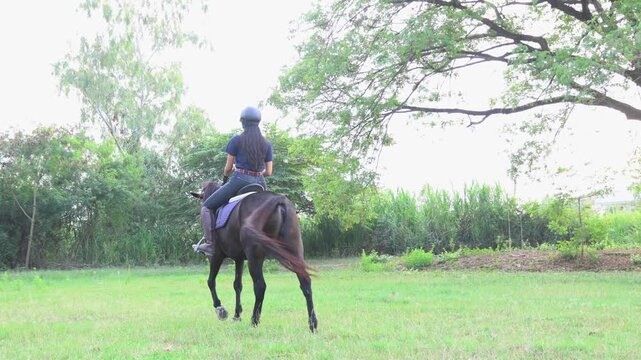 Asian female equestrian athletes coaches wearing helmets practical attire practice outdoor training ground jogging slowly across grass evening familiarizing themselves horses  graceful movements.