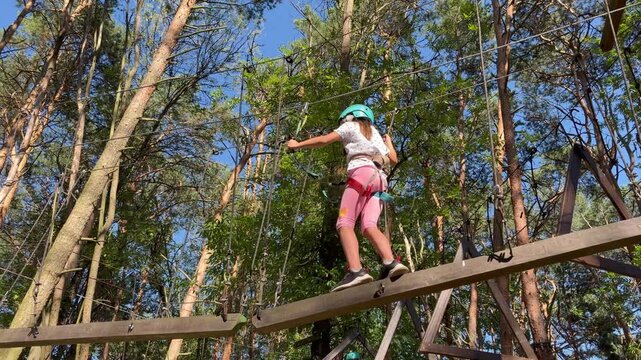 active recreation for children. A girl in protective gear navigates the rope maze