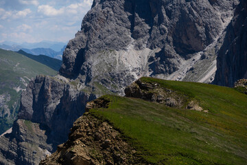 Obraz premium idyllic rolling hills landscape with blooming meadows and alpine mountain peaks in the background on a beautiful sunny day with blue sky and clouds, Alpe di Cisles, Seceda Ridgeline, Dolomiti 