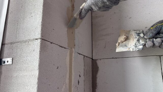 A man's hands plaster a wall with cement mortar