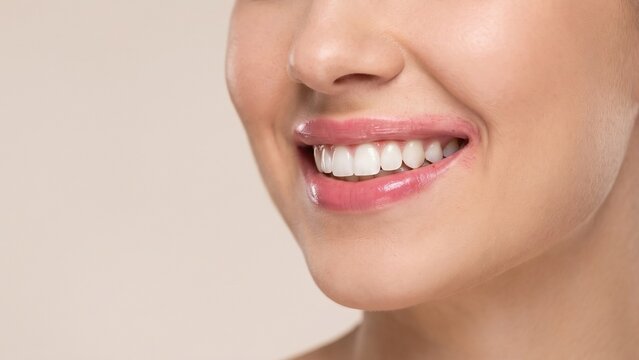 Close-up portrait of a woman with a natural smile showing white teeth, highlighting dental health, oral hygiene, and skincare cosmetics concepts.