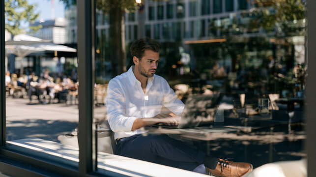 Remote Work: Business Professional Working on Laptop Near Window at Modern Caf&eacute;