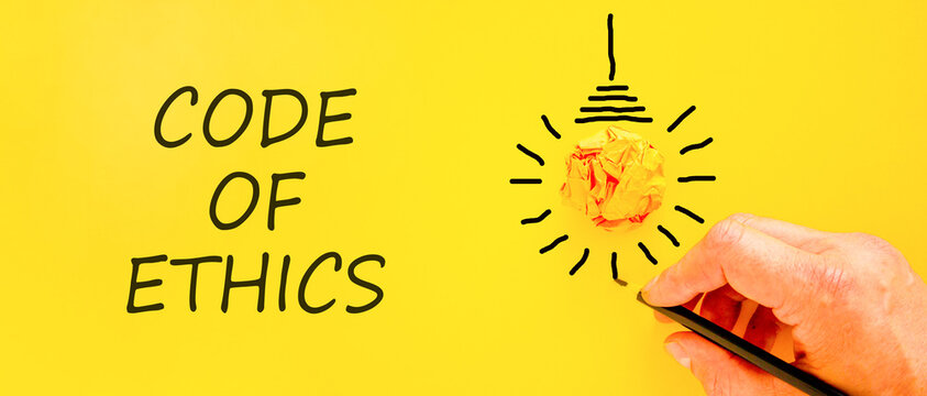 Code of ethics words symbol. Concept words Code of ethics on beautiful yellow paper. Beautiful yellow background. Light bulb icon. Businessman hand. Business Code of ethics concept. Copy space.