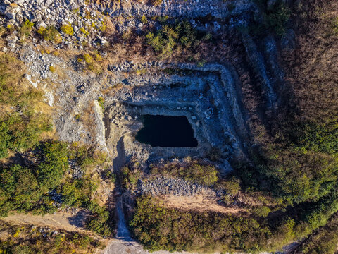 Aerial view of Manton Quarry Road showing the deep excavation pit with rocky terraces and surrounding vegetation Calcium, Queensland, Australia.