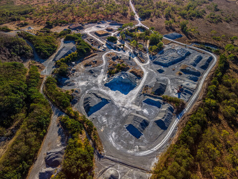 Aerial view of Manton Quarry Road showing piles of crushed stone, industrial excavation areas, and surrounding dry vegetation in Calcium, Queensland, Australia.