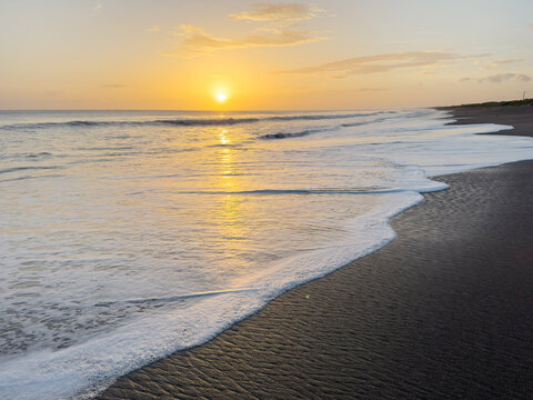 Sunrise over the ocean with waves at the beach in the morning