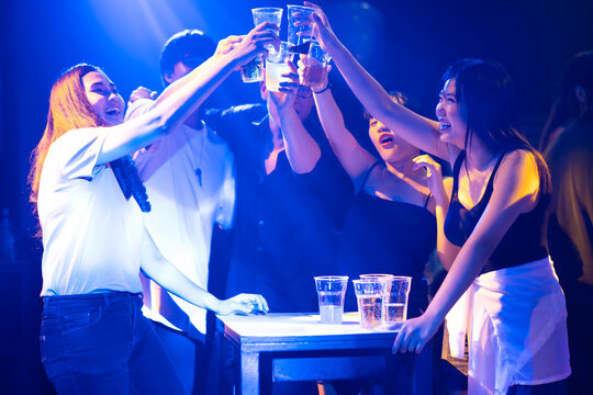 Group of friends having drinks and toasting at the night club party. diverse young people dancing in night club. Nightlife and disco dance party concept. Fun music festival