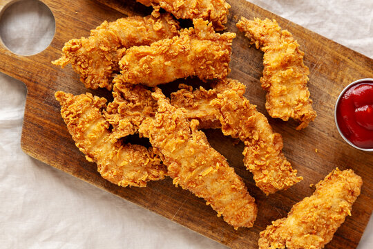 Organic Crispy Chicken Strips with Ketchup on a Wooden Board, top view.