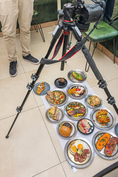 Overhead Food Photography Setup with Tripod Camera Capturing Assorted Gourmet Brunch Dishes on Metal Plates
