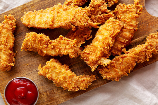 Organic Crispy Chicken Strips with Ketchup on a Wooden Board, top view. Close-up.