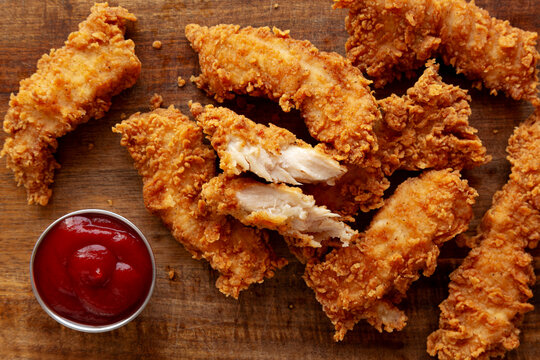Organic Crispy Chicken Strips with Ketchup on a Wooden Board, top view. Close-up.