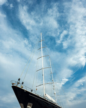 Impressive low angle view of a tall ship's mast and rigging reaching toward the blue sky