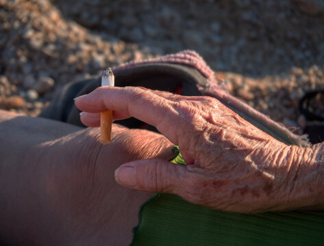 Wrinkled hand with cigarette of old Greek woman 
