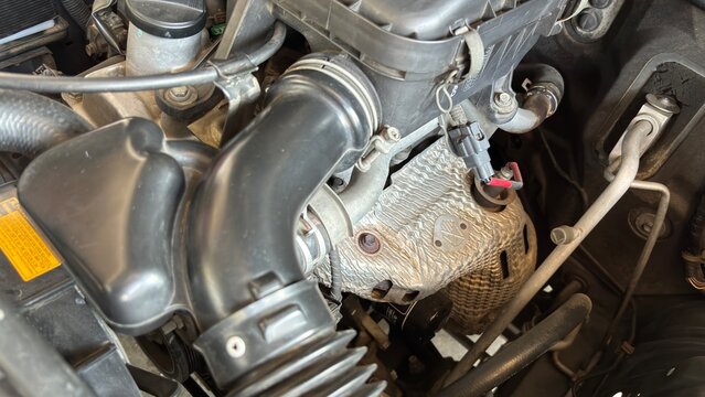  Detailed view of automobile engine compartment showing intake manifold, black tubing, metallic parts, and hoses. Represents automotive maintenance, diagnostics, and mechanical engineering.