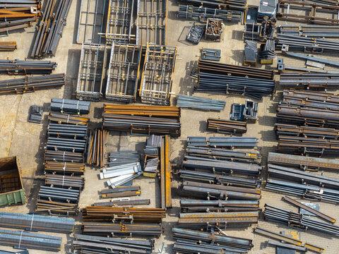 Aerial view of an industrial metal processing and manufacturing plant with organized stacks of steel beams and metal profiles in an outdoor storage yard in Poland.