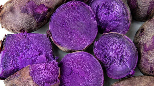 Fresh purple yam tubers cut in half showcasing vibrant ube color, natural texture and raw ingredients for Filipino desserts