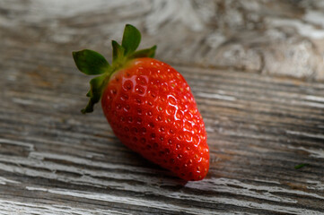 Freshly picked strawberry resting on rustic wooden surface with natural lighting © Михаил Шорохов