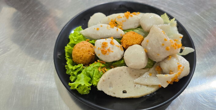 Assorted boiled fish balls (or mixed boiled fish balls) topped with fragrant golden fried garlic, lettuce. Includes rugby-shaped fish balls, round balls,  dumplings, fried shrimp balls.
