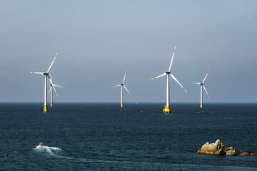 Offshore Wind Turbines in Blue Sea Near Rocky Coast © ChuThi
