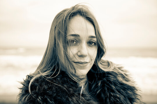 Melancholy and pensive young woman dreaming and thinking outdoor with ocean beach in background in autumn season - Relaxing lifestyle female people in outdoor leisure - Black and white editing