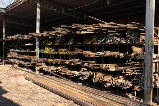 Wide view of industrial steel warehouse with stacked metal pipes, bars and profiles stored on heavy steel racks