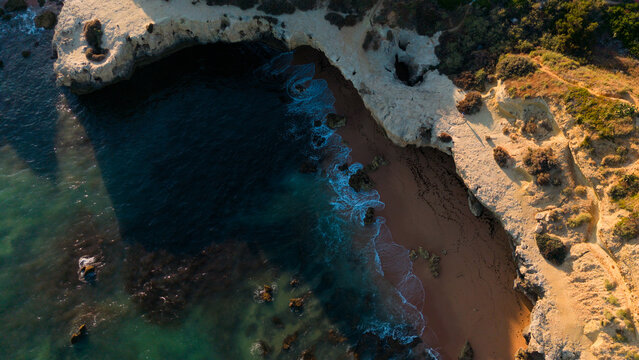 serene aerial view of rocky coastline with ocean waves and sandy beach, travel photography scene with natural and brown tones, aerial perspective of coastal landscape, beach Praia dos Aveiros Portugal