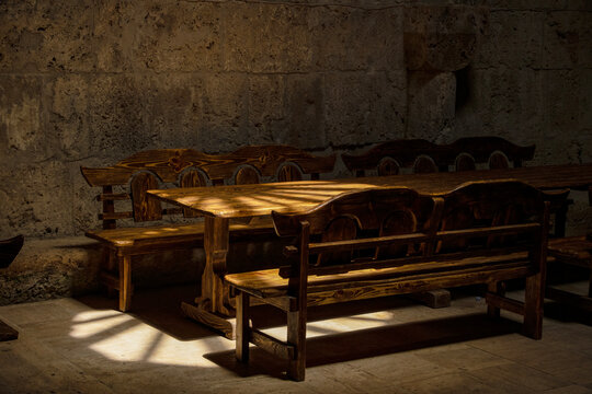 This rustic wooden dining set features a heavy table and matching benches crafted with a dark, aged finish.Dining table and benches in the monastery refectory, Armenia.