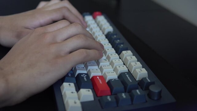 Close-up side view of hands typing on a custom mechanical computer keyboard.