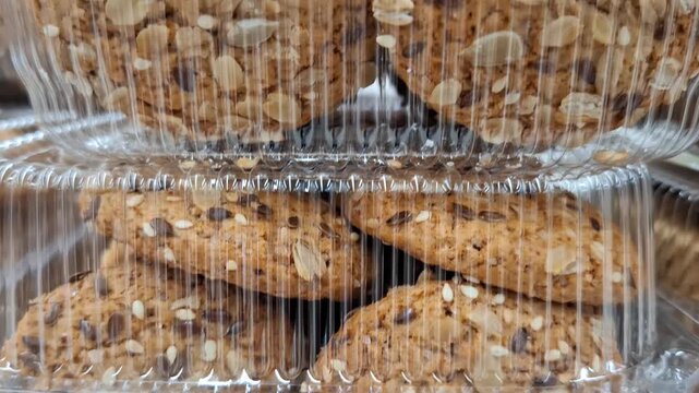 Packaged cookies or baked snacks in a clear container. Sweet bakery food, convenient dessert, market display, fresh treat.