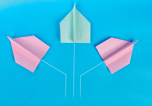 Three colorful paper airplanes with branching white flight paths on blue background

