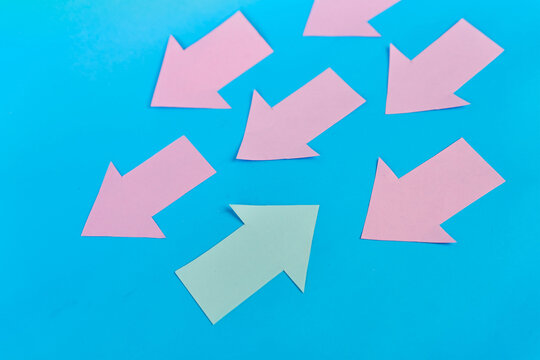 Green arrow pointing opposite to pink arrows on blue background

