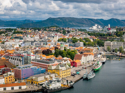 Aerial view of the historic harbor and city center with colorful buildings, docked ships, and mountains in the background in Stavanger, Rogaland, Norway.