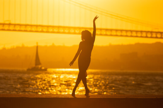 Dancer performs at sunset by the bridge with boat in the background