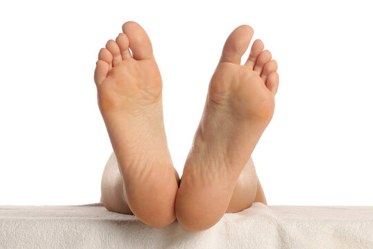 Soles of bare feet resting on white towel, healthy clean skin close-up, foot care and pedicure concept on white background.