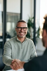 Fototapeta premium Smiling businessman shaking hands in a modern office meeting for business agreement banner and website background