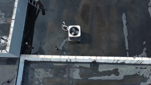 Rain and water damage across industrial commercial business rooftop and flat roof on rubber sealed roofing causing leaks, rainfall tears, and leaking into building exterior from above drone aerial 4k