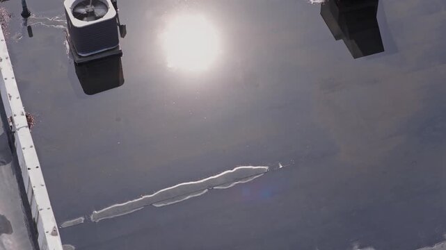 Rain and water damage across industrial commercial business rooftop and flat roof on rubber sealed roofing causing leaks, rainfall tears, and leaking into building exterior from above drone aerial 4k