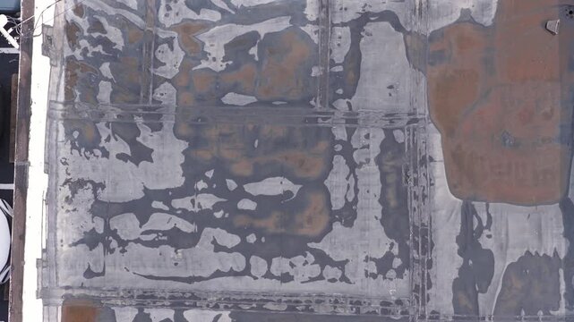 Rain and water damage across industrial commercial business rooftop and flat roof on rubber sealed roofing causing leaks, rainfall tears, and leaking into building exterior from above drone aerial 4k