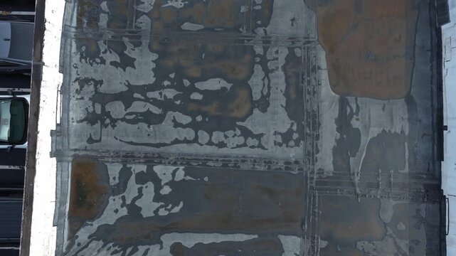 Rain and water damage across industrial commercial business rooftop and flat roof on rubber sealed roofing causing leaks, rainfall tears, and leaking into building exterior from above drone aerial 4k